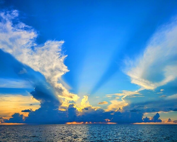 A sunset over the ocean with a clear sky and clouds. - Cozy Modern Apartment -Close to Beaches, Dive Centers- 4 minutes away (GEORGE TOWN)