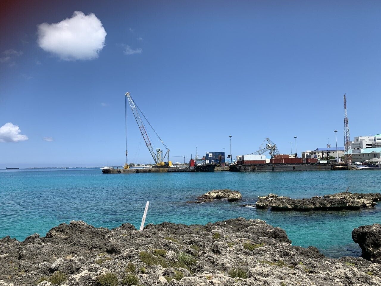 Un puerto costero con una grúa grande, un barco y edificios industriales.