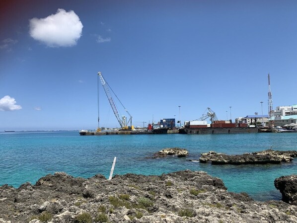 Ein Küstenhafen mit einem großen Kran, einem Schiff und Industriegebäuden.