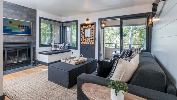Un salon moderne avec une cheminée, un canapé, une table basse et une grande fenêtre.