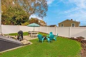 Un jardin avec une table et des chaises de patio, un barbecue et une piscine.