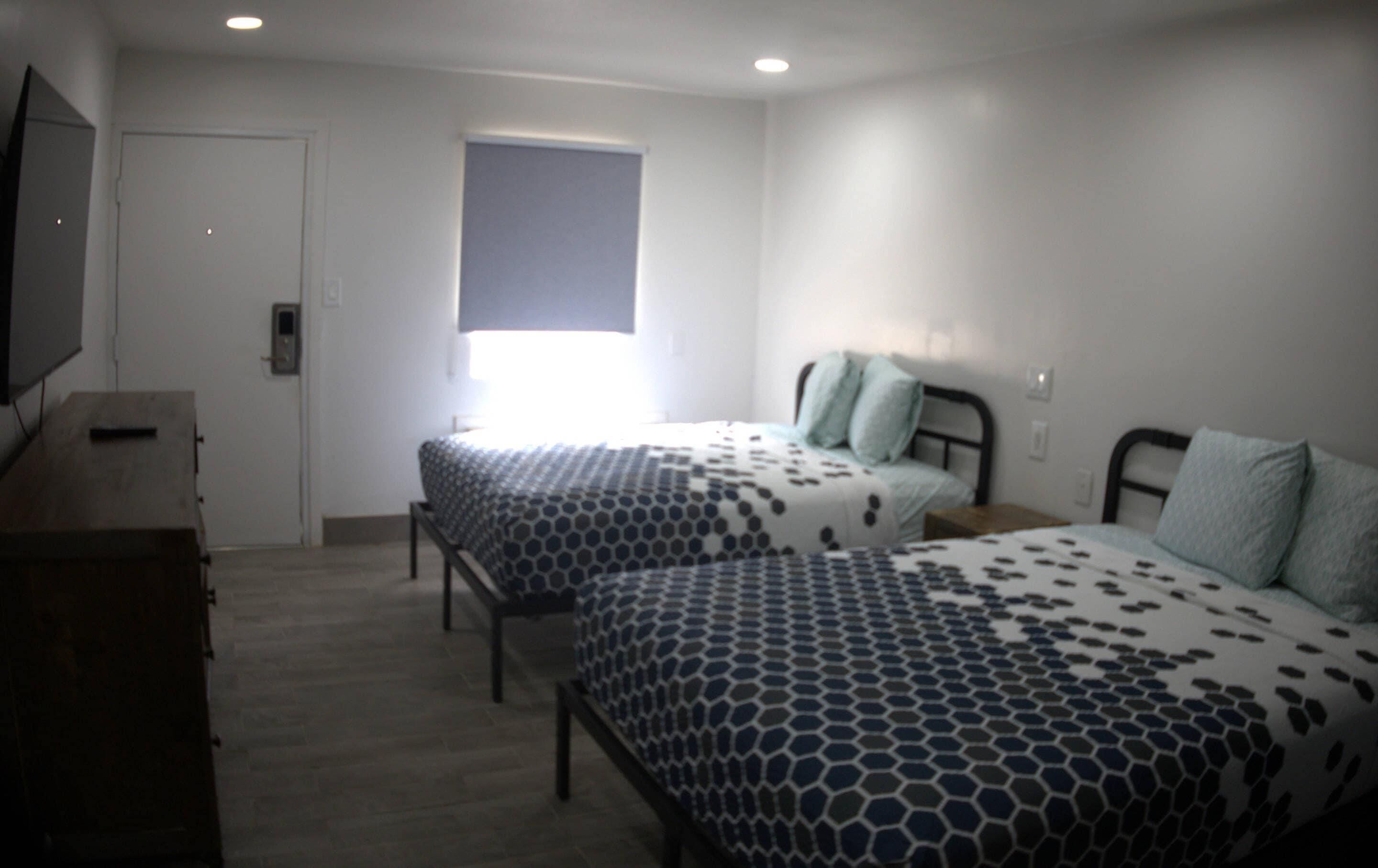 Un dormitorio con dos camas, un televisor y una ventana.