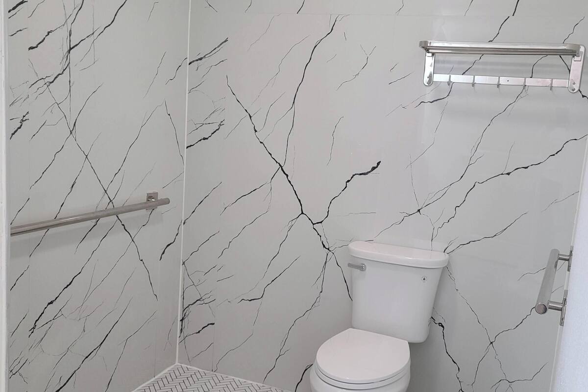 A bathroom with a toilet, a shower area, and a towel rack.