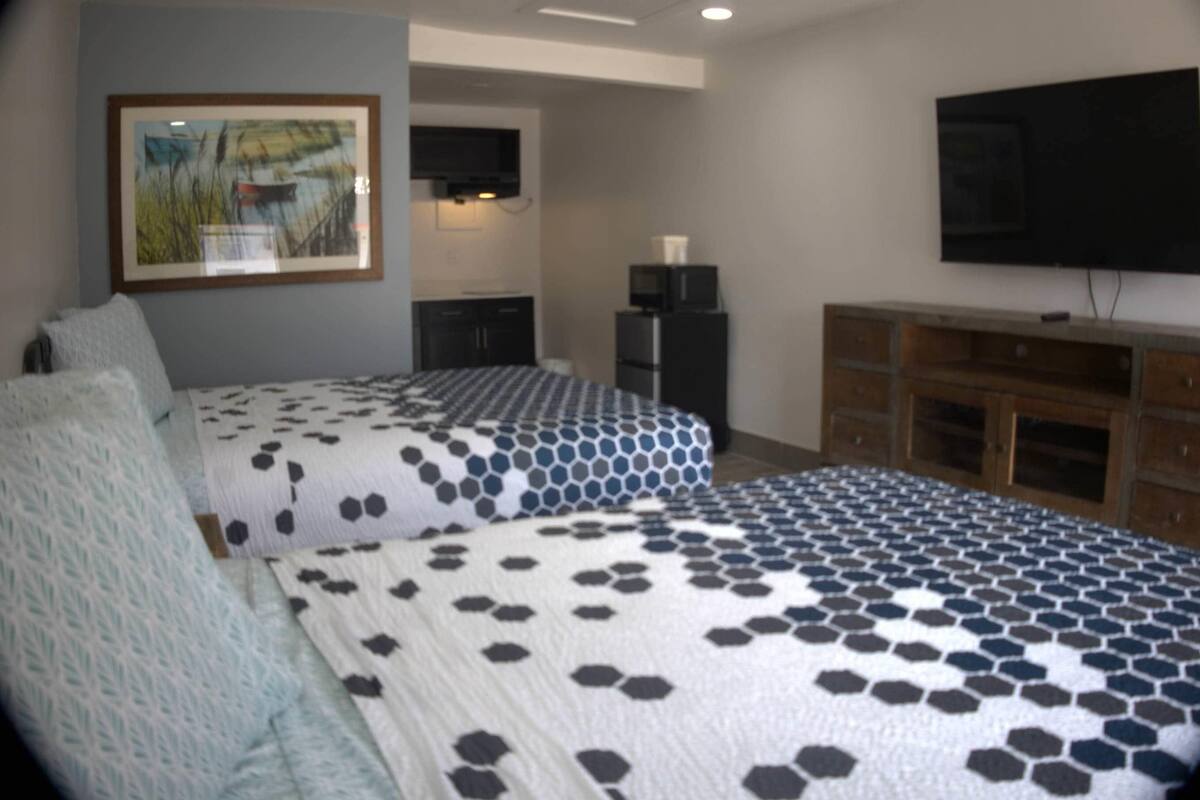 A bedroom with two beds, a TV, a refrigerator, and a wooden cabinet.