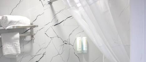 A bathroom with a toilet, a shower with a curtain, and a marble wall.