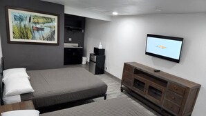A bedroom with a bed, a TV, a dresser, and a painting on the wall. - Rodeway Inn (Livingston)