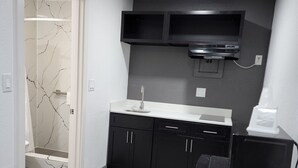 A compact kitchen with dark cabinetry, a white countertop, and a built-in microwave.