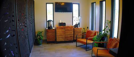 A modern living room with a sofa, chairs, a coffee table, and a TV mounted on the wall.