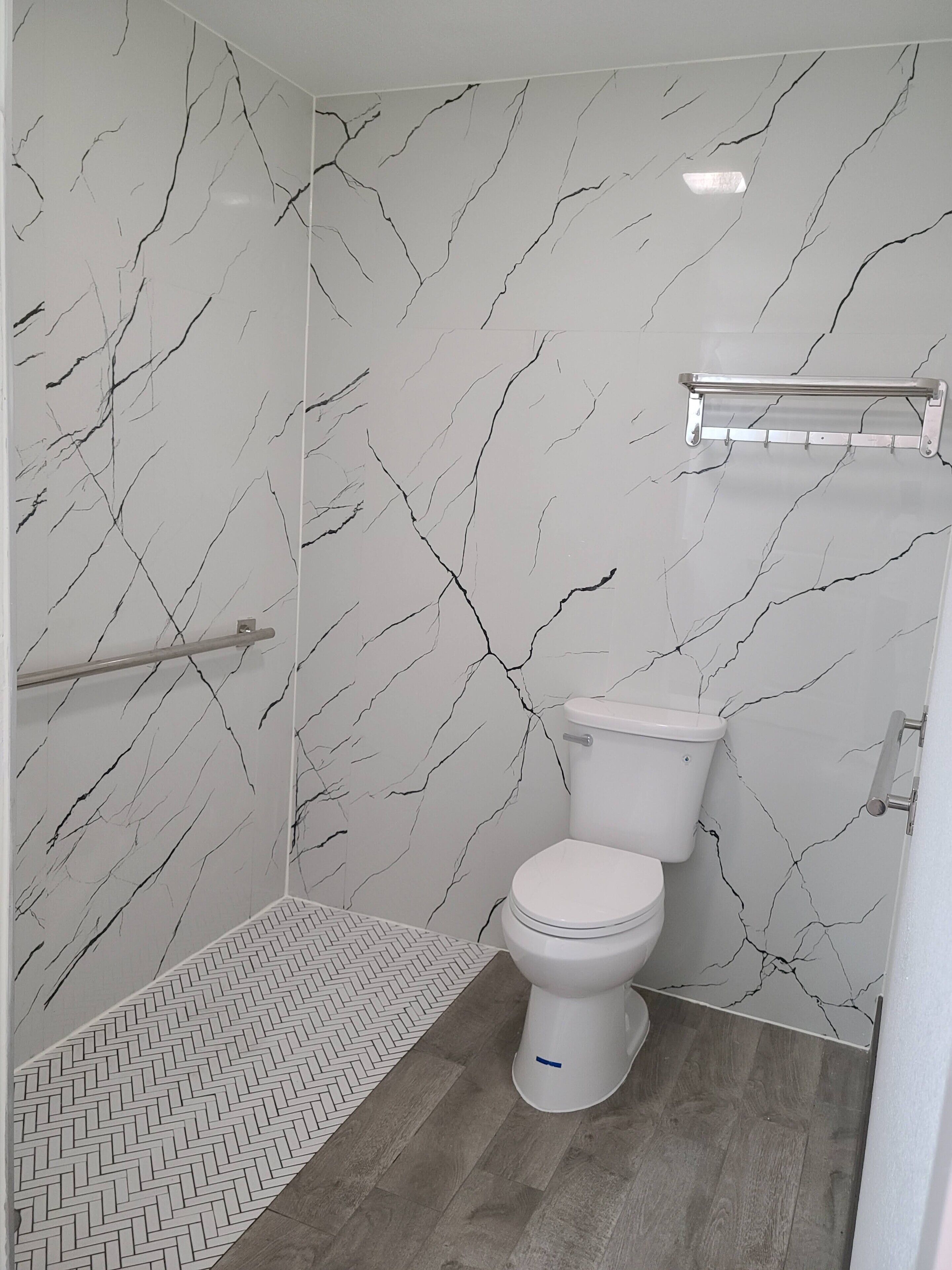 A bathroom with a toilet, a shower area, and a towel rack.