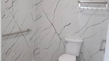 A bathroom with a toilet, a shower area, and a towel rack.
