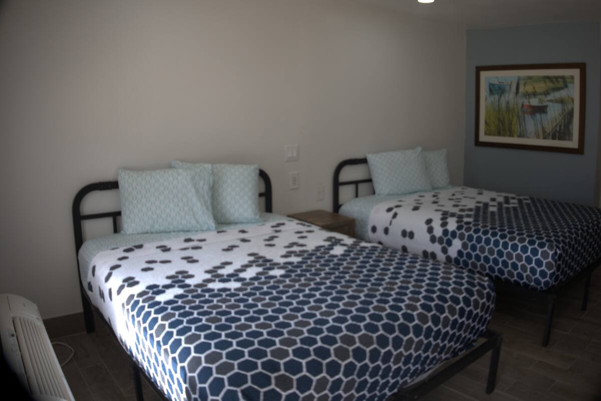 Two single beds with patterned bedding, a radiator, and a painting on the wall.