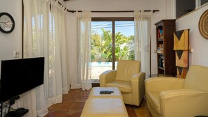 A living room with a television, a sofa, an ottoman, and a bookshelf. - 'Villa Casa Colina'with Pool and Wi-Fi (Albir)
