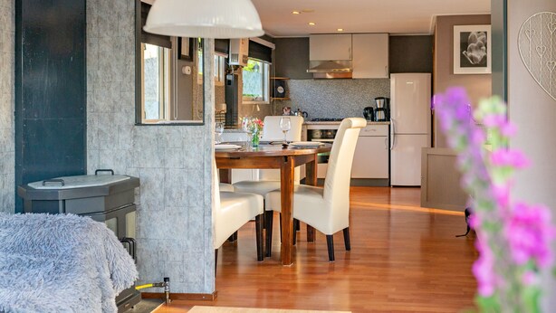 A modern kitchen with a dining area, wooden flooring, and a large window. - Romantic chalet on the Veluwe (Hulshorst)