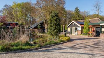 A building with a gravel driveway, a pond, and trees.