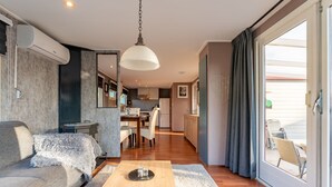 A modern living room with a sofa, coffee table, and a view of the kitchen and dining area. - Romantic chalet on the Veluwe (Hulshorst)