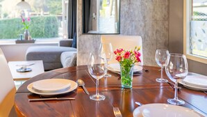 A dining table set with plates, cutlery, and wine glasses, a vase with flowers, and a 'Welcome' sign on the wall. - Romantic chalet on the Veluwe (Hulshorst)