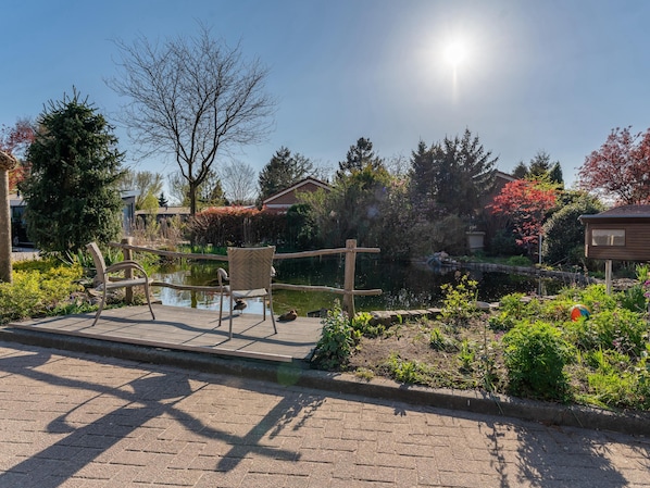 A garden with a pond, a wooden bridge, and a chair.
