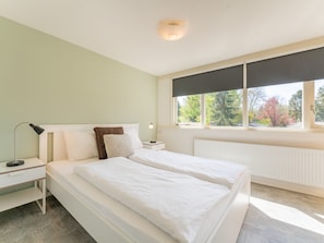 Relax in this serene bedroom with a large bed, bedside tables, and a window offering a view of the surrounding trees.