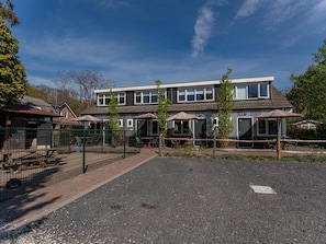 Stylish two-story building with a flat roof and large windows, surrounded by a gravel driveway and outdoor seating area.