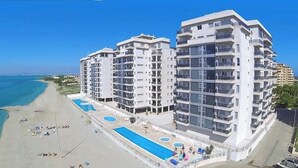 Un hôtel moderne à plusieurs étages, doté d’une piscine et situé en bord de mer.