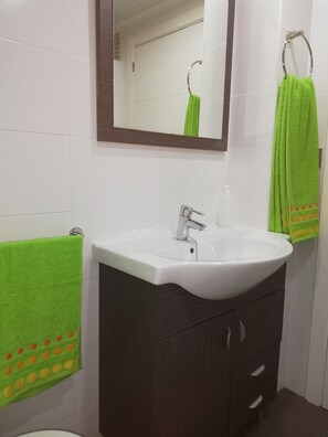 Une salle de bain avec un lavabo blanc, un meuble en bois foncé et un miroir au-dessus du lavabo.