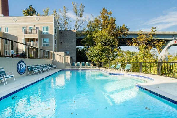 A swimming pool with lounge chairs and a building with a sign.