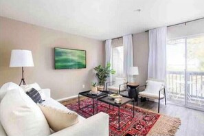 A modern living room with a sofa, armchairs, a coffee table, and a large window with curtains.