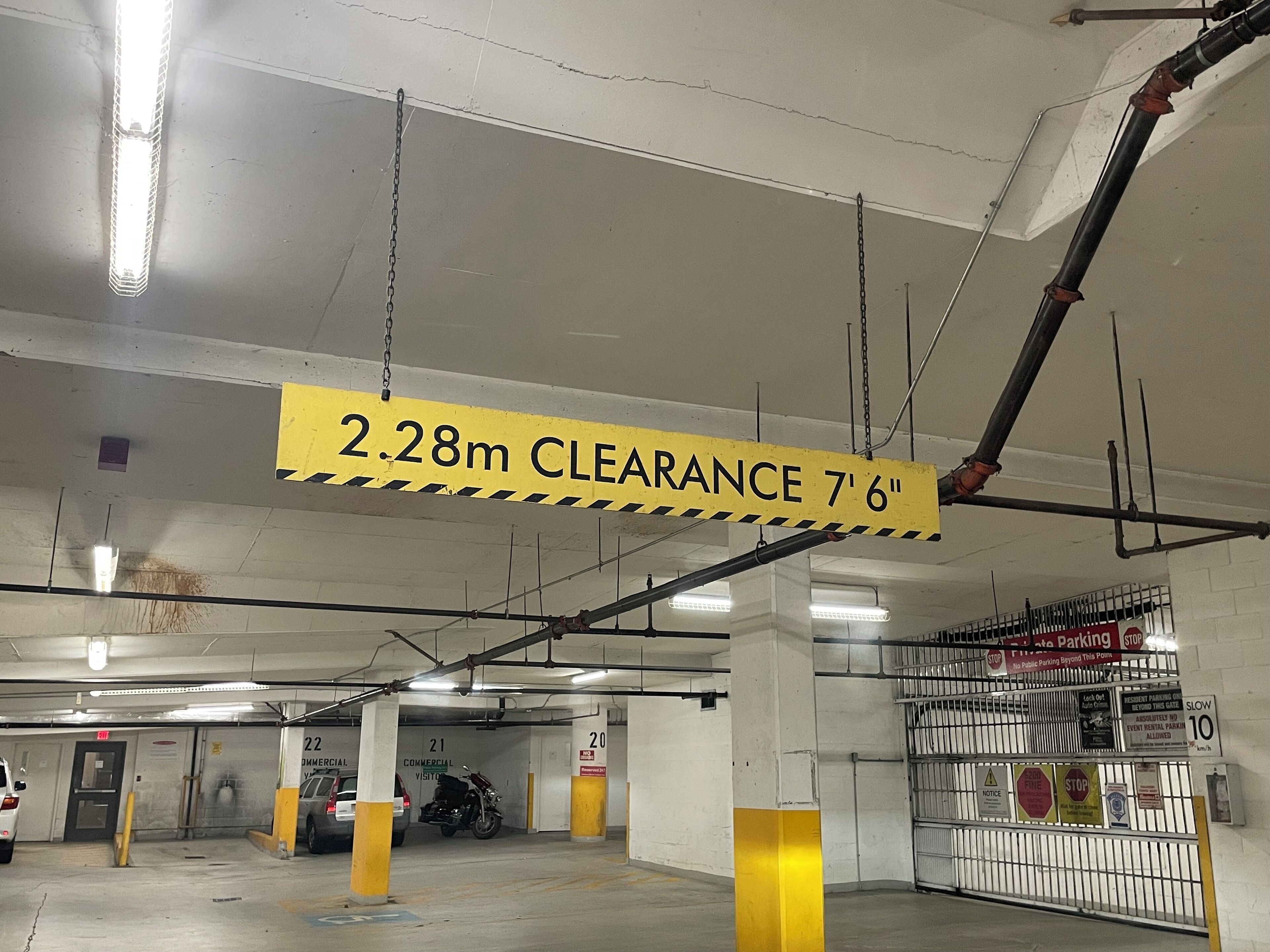 Un aparcamiento con un cartel amarillo que indica una altura máxima de 2,28 metros.