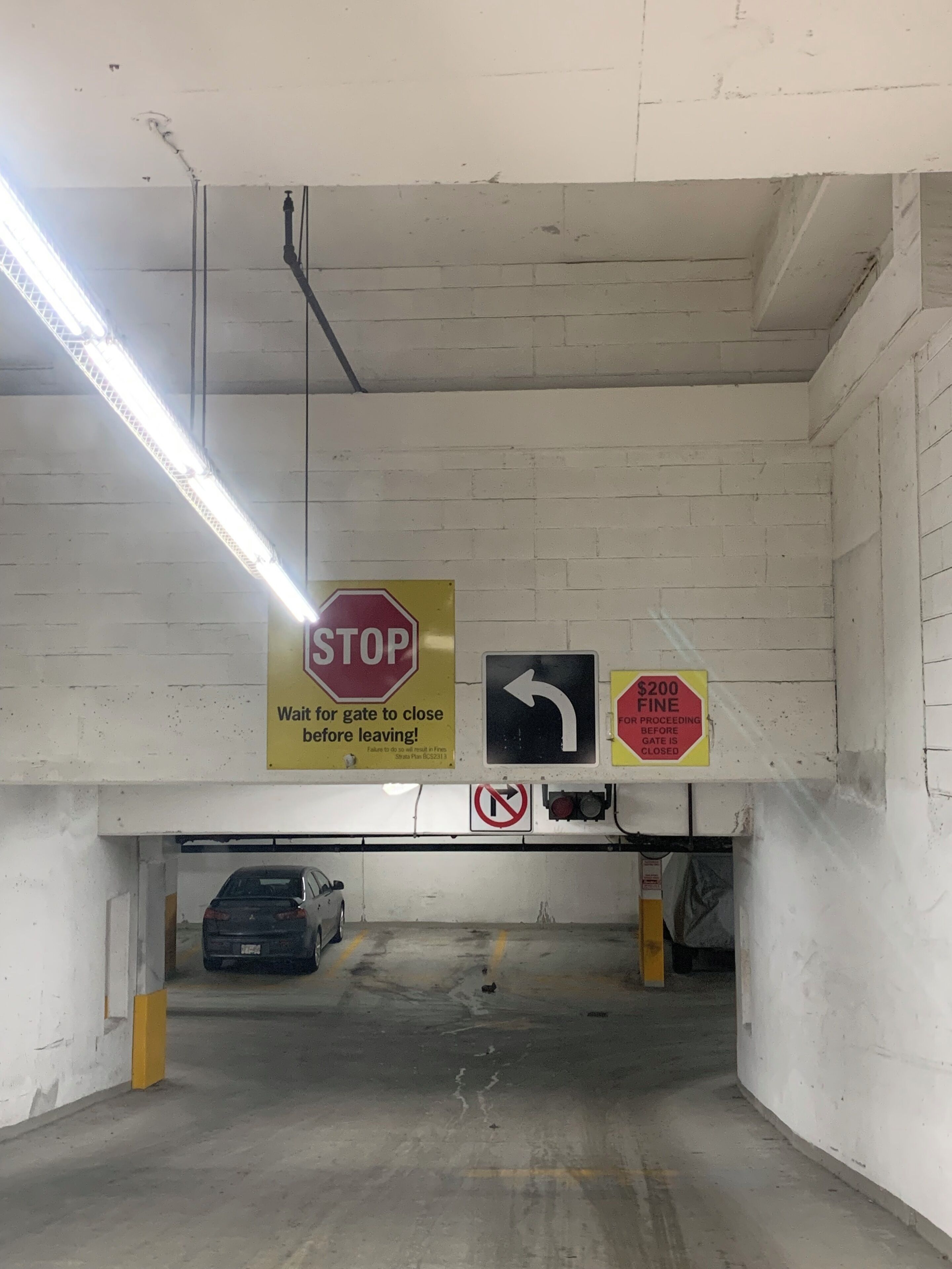 A parking garage with a stop sign, directional arrow, and a $200 fine sign.