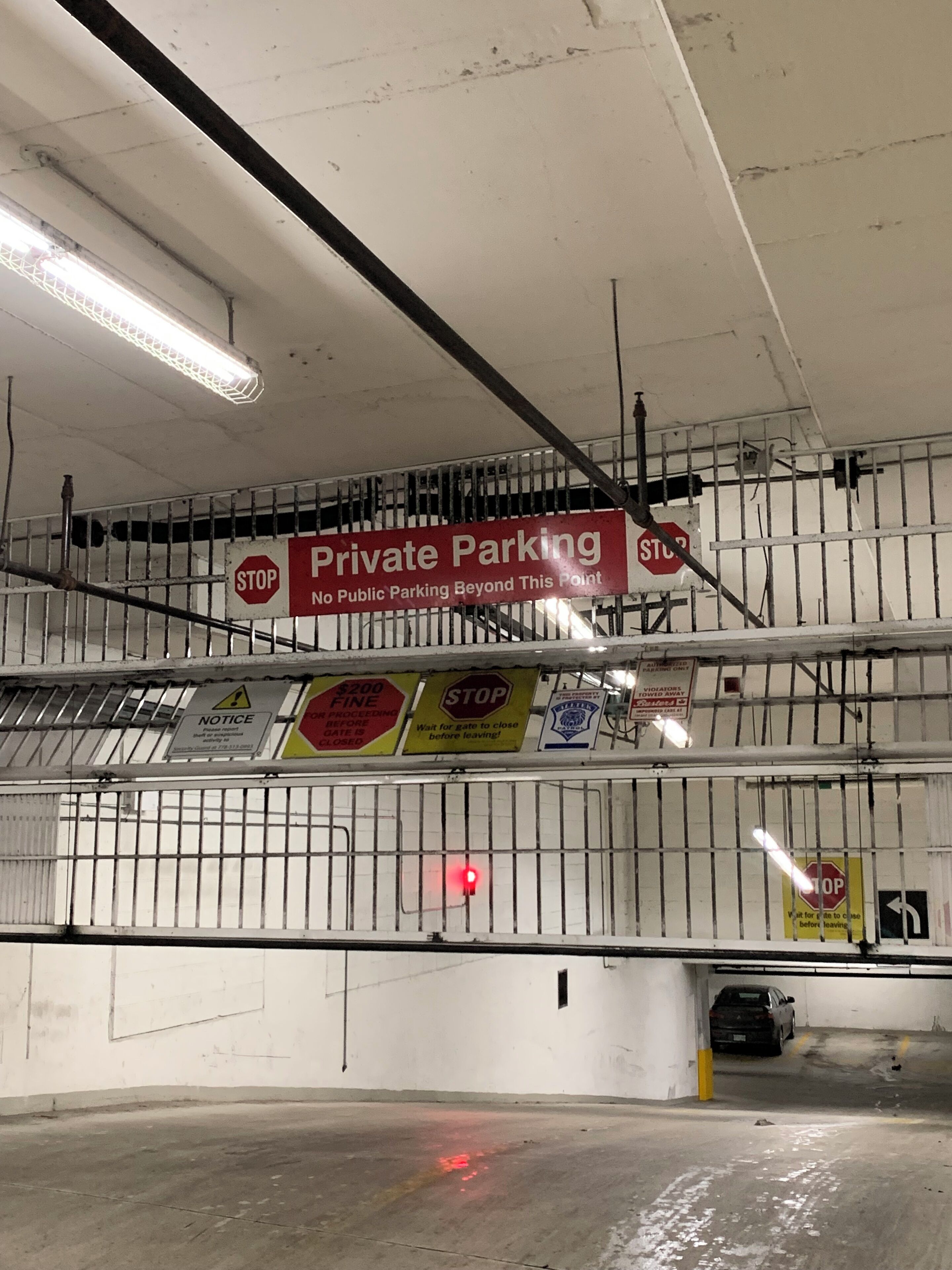 Ein überdachter Parkbereich mit mehreren Schildern, die privaten Stellplatz reserviert anzeigen, eine Strafe von 200 Dollar bei Nichteinhaltung und ein rotes Stoppschild.