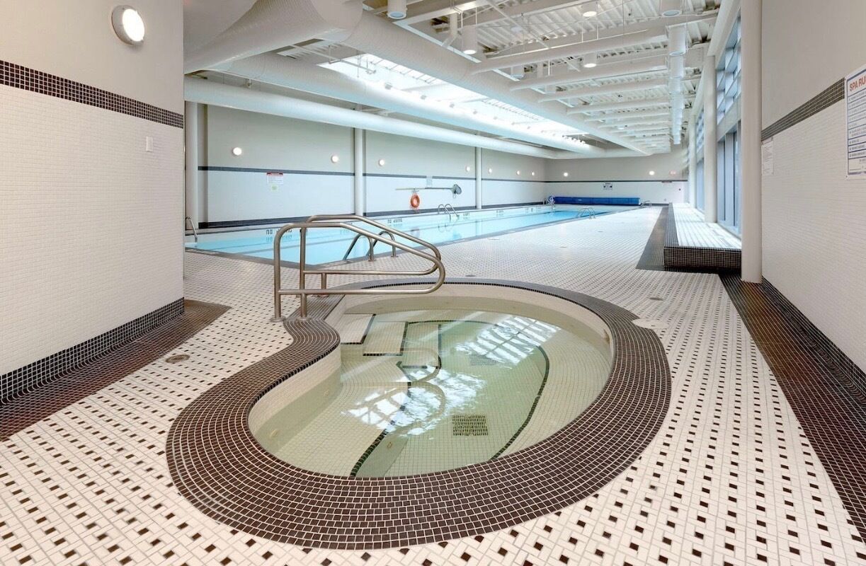 Una piscina interior con suelo de baldosas y zona central de natación.