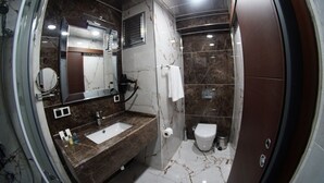 Un bagno con lavabo in marmo, uno specchio, un water e una zona doccia.