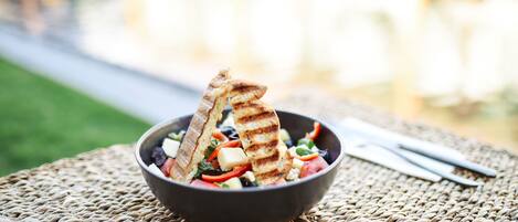 A bowl of salad with grilled bread on a woven mat.