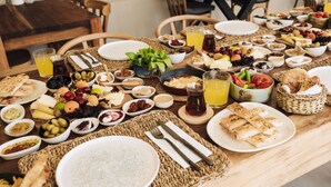 A table set with various breakfast items including bread, fruits, cheeses, and beverages. - Enso Alacati (Cesme)