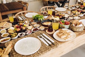 Una mesa dispuesta con diversos alimentos para el desayuno, como pan, frutas, quesos y bebidas.