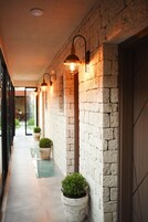 Un pasillo con pared de piedra, plantas en macetas e iluminación empotrada.
