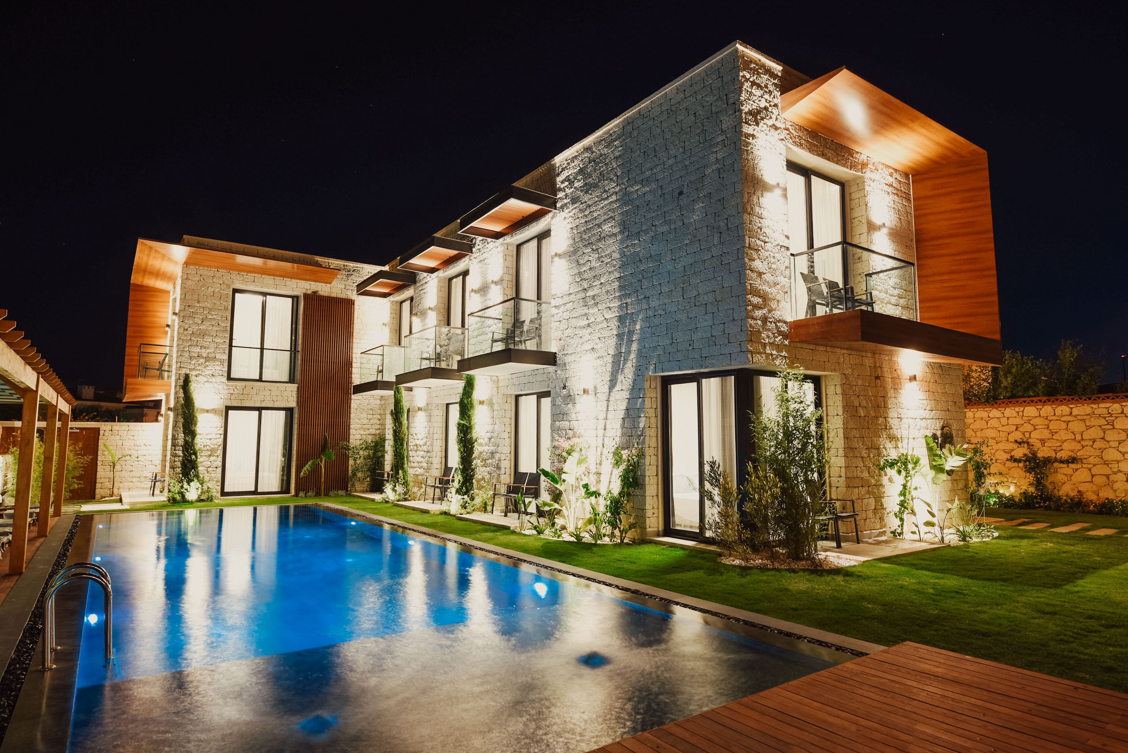 Une maison moderne dotée d’une piscine, de murs en pierre et de balcons en bois.