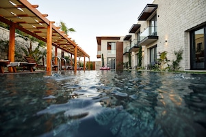 Un hotel moderno con piscina, zona de estar exterior y una pared de piedra.