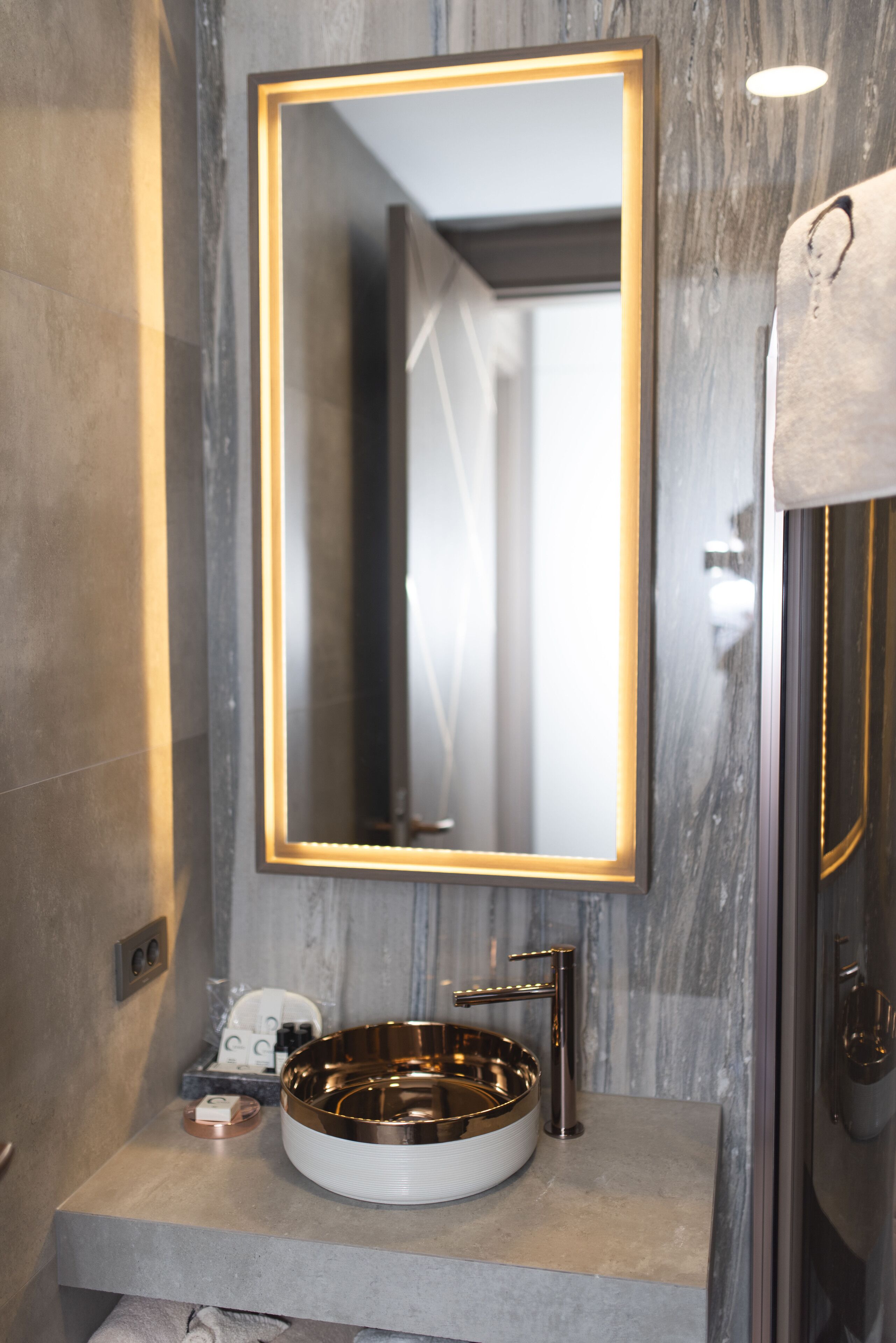 A bathroom with a large mirror, a round sink, and a shower area.