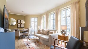 Een woonkamer met een bank, fauteuil en een eethoek met een tafel en stoelen.