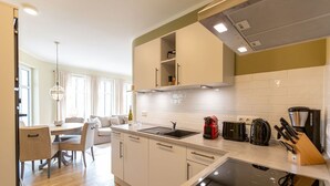 Een moderne keuken met witte kastjes, een inbouwvaatwasser en een aanrecht met koffiezetapparaat en broodrooster.