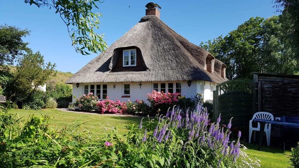 A thatched-roof cottage with a garden in front.