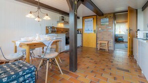 A kitchen with a wooden table, chairs, and a hanging light fixture.