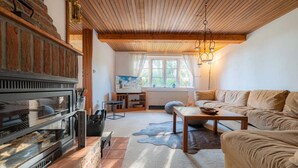 A cozy living room with a fireplace, a sofa, a coffee table, and a window with curtains.