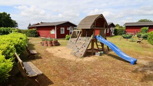 A playground with a slide, climbing wall, and swings. - House Zempin - Holiday homes Räuberkuhle 1 (Koserow)
