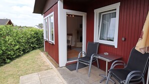 A red building with a patio area featuring two chairs and a small table. - House Zempin - Holiday homes Räuberkuhle 1 (Koserow)