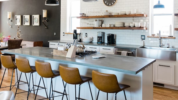 A modern kitchen with a central island, bar stools, pendant lighting, and a clock on the wall. - Luxurious, downtown loft with a warm, family feel (Sheridan)