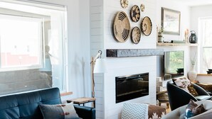 A modern living room with a fireplace, a sofa, a coffee table, and a TV mounted on the wall. - Luxurious, downtown loft with a warm, family feel (Sheridan)