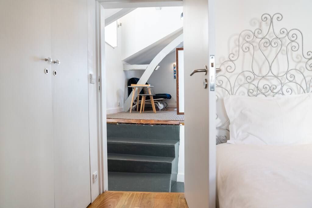 A bedroom with a bed, a staircase leading to a loft area, and a metal headboard.