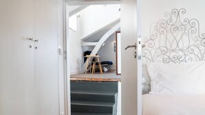 Een slaapkamer met een bed, een trap naar een vide en een metalen hoofdbord.